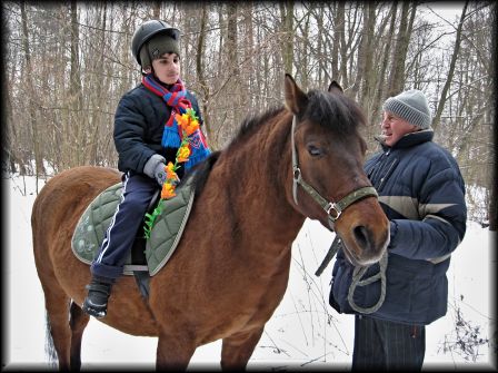 na zdjęciu chłopiec na koniu trzyma kolorową palmę